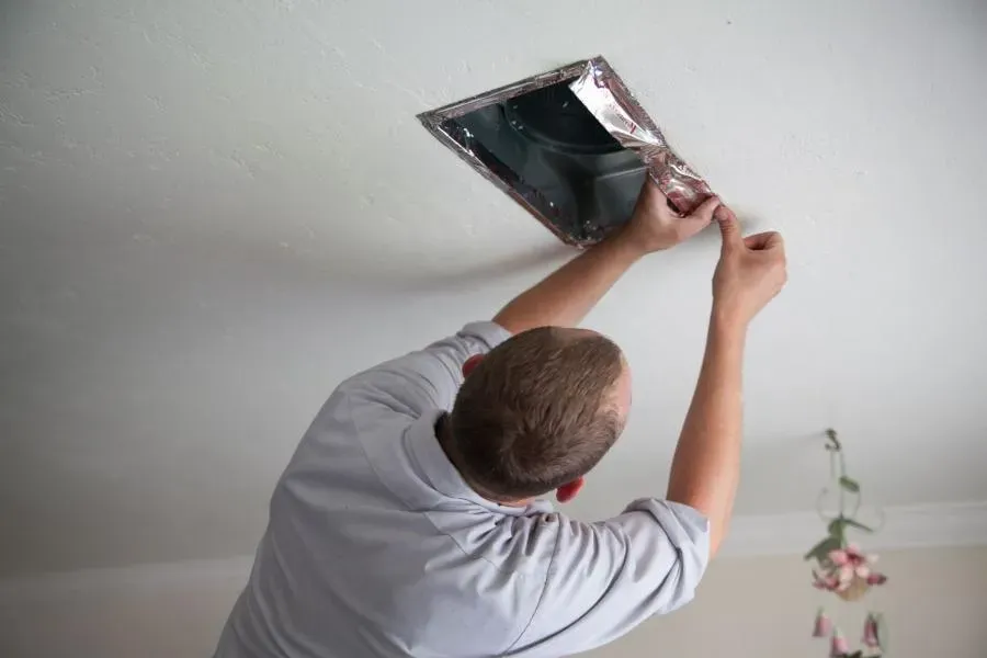 A technician from Moore Home Services in Brea inspecting a ceiling vent.